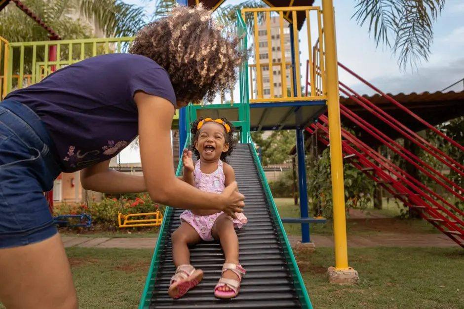 Ibu dan anak bermain di taman sederhana dengan mainan bekas